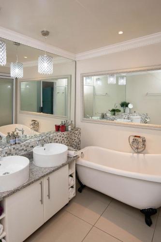 a bathroom with two sinks and a tub and mirrors at Oleander Guest House in Kimberley