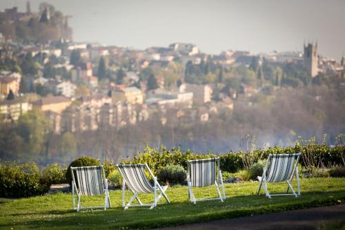 three chairs sitting in the grass in front of a city at Hotel du Léman - Jongny in Vevey