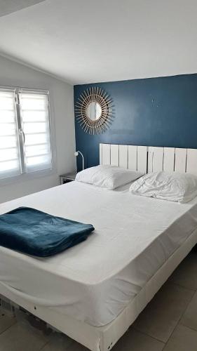 - un grand lit blanc dans une chambre dotée d'un mur bleu dans l'établissement Pavillon climatisé avec extérieur et piscine collective - 4PAV87, à Saint Pierre La Mer