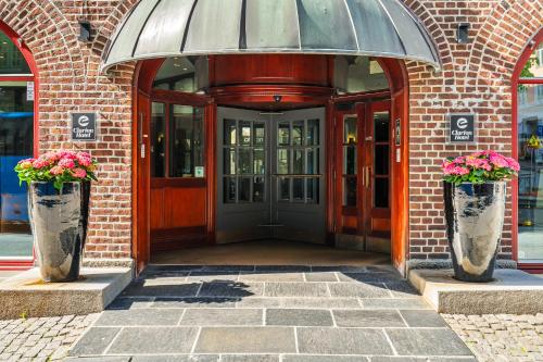 an entrance to a building with two vases with flowers at Home Hotel Bryggen in Bergen