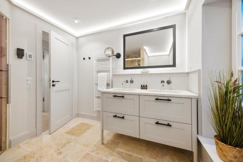 une salle de bain blanche avec un lavabo et un miroir dans l'établissement Gardenlodge 2, à List auf Sylt