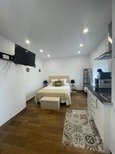a white bedroom with a bed and a kitchen at La casuca de Candela in Santillana del Mar