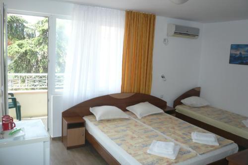 a bedroom with two beds and a large window at Къща за гости Мишел in Nesebar