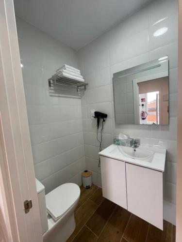 a white bathroom with a toilet and a sink at La casuca de Candela in Santillana del Mar