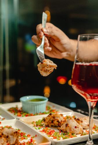 a person eating food with a fork and a glass of wine at The Peninsula Chittagong Limited in Chittagong