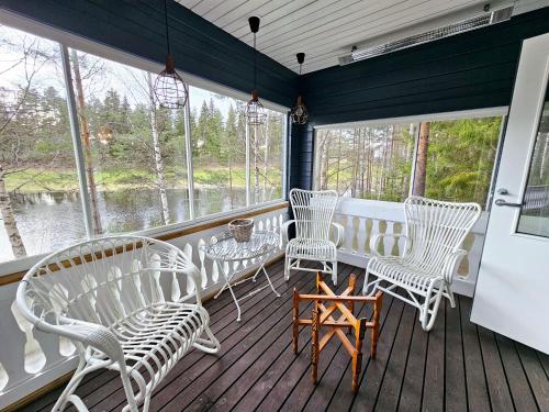 a screened in porch with white chairs and a table at Kerimaa Golf Chalet close to Savonlinna in Savonlinna