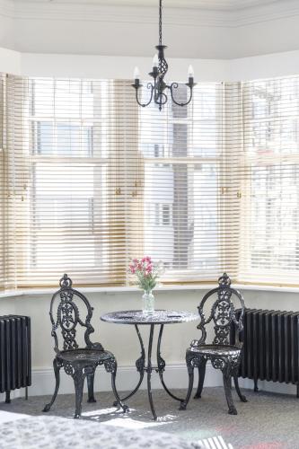 a table and two chairs in a room with windows at Finest Retreats - Pittodrie Guest House - Apartment 6 in Brighton & Hove