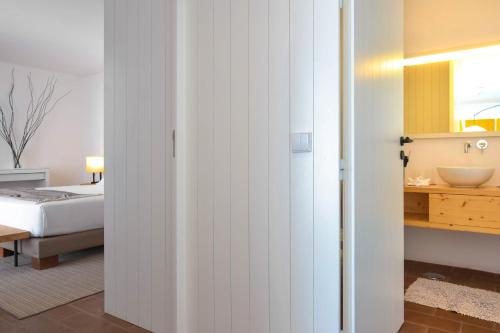um quarto com uma cama e uma casa de banho com um lavatório em The Lince Ecorkhotel Évora em Évora