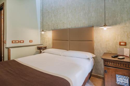 um quarto com uma grande cama branca e uma secretária em Hotel Il Convento em Nápoles