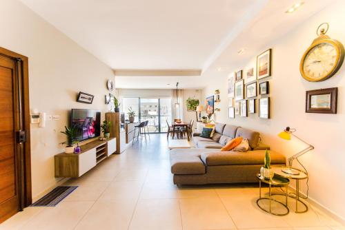 a living room with a couch and a clock on the wall at MedAbode - Bright & Spacious Stay in Swieqi, Malta in Is-Swieqi