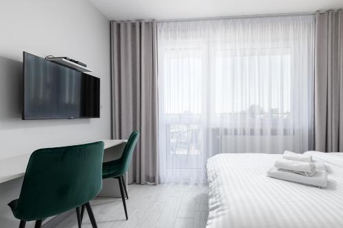 a bedroom with a bed and a desk and a television at RentPlanet - Apartamenty Pileckiego in Warsaw