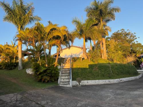 a house with palm trees and a set of stairs at Chácara Canaã in Jambeiro