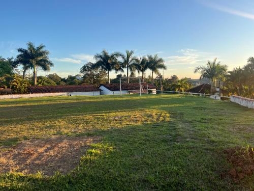 a large grass field with palm trees in the background at Chácara Canaã in Jambeiro