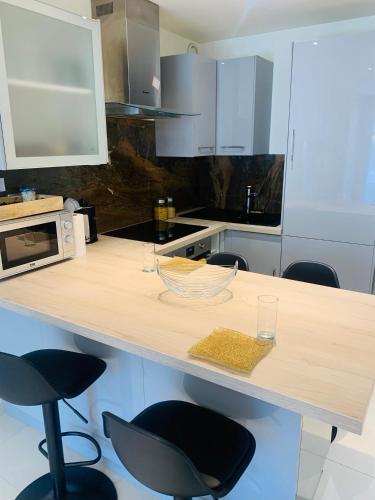 une cuisine avec un comptoir avec deux chaises et un four micro-ondes dans l'établissement Location T2, à Fréjus