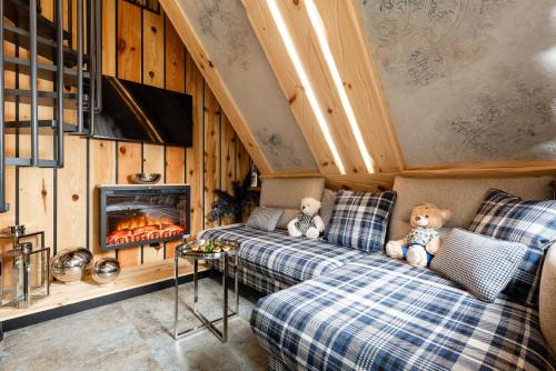 two teddy bears sitting on a couch in a room with a fireplace at Brzozowa Osada - Premium Chalets Zakopane in Zakopane