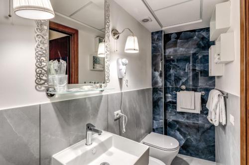 a bathroom with a sink and a toilet and a mirror at Hotel Santa Prassede in Rome