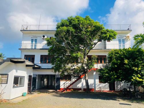 a white building with a tree in front of it at Blue Ocean Hotel in Matara