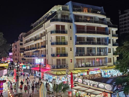 ein hohes weißes Gebäude auf einer Stadtstraße bei Nacht in der Unterkunft Kaya Apartments in Sonnenstrand