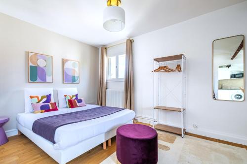 a bedroom with a large bed and a purple stool at Studio coloré proche Paris Parc des Princes in Issy-les-Moulineaux