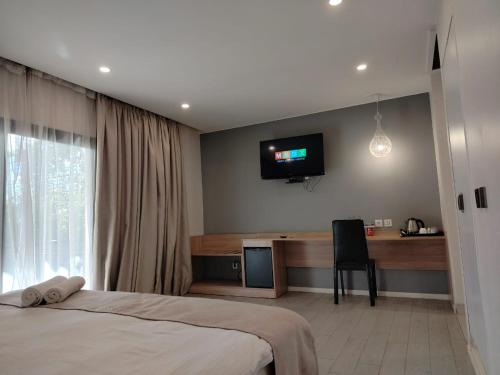 a bedroom with a bed and a desk and a television at Flora Hotel Ivato International Airport in Antananarivo