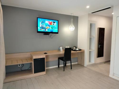 a room with a desk with a television on a wall at Flora Hotel Ivato International Airport in Antananarivo