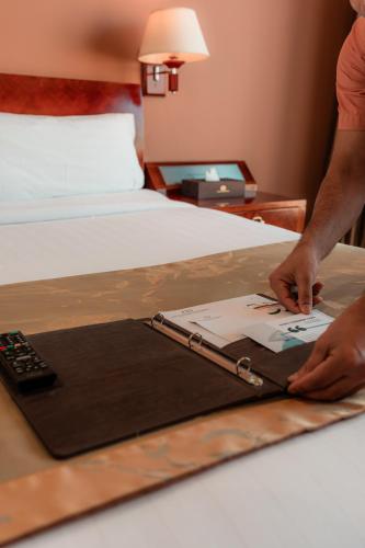 a person is typing on a laptop on a bed at The Peninsula Chittagong Limited in Chittagong