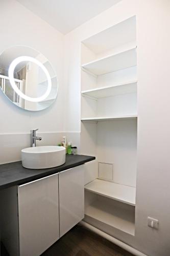 une salle de bain blanche avec un lavabo et un miroir dans l'établissement Appart Faubourg St Denis 4 personnes, à Paris