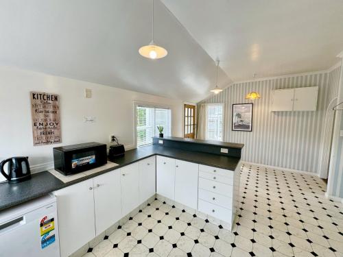 a kitchen with white cabinets and a black counter top at Harbourview Khandallah Charm in Wellington