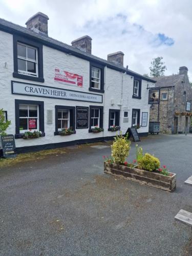 a white building with flowers in front of it at Craven Heifer in Carnforth