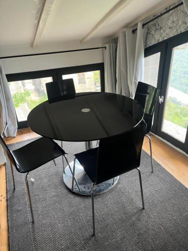 - une table et des chaises noires dans une chambre avec fenêtres dans l'établissement Bienvenue chez nous, à Lantosque