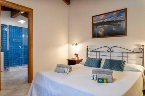 a bedroom with a bed with blue pillows on it at Ginestre Cottage with pool in the Nature Park of Porto Conte in Santa Maria la Palma