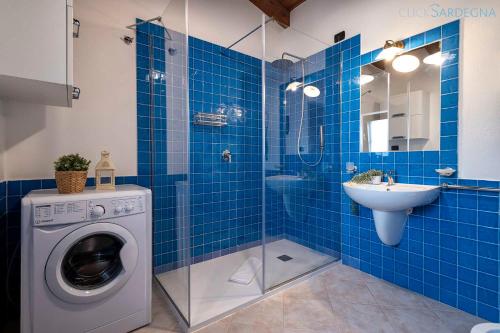 a blue tiled bathroom with a washing machine and a sink at Ginestre Cottage with pool in the Nature Park of Porto Conte in Santa Maria la Palma