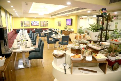 a restaurant with tables and chairs with food on them at Sarovar Portico Naraina, Hotel in New Delhi
