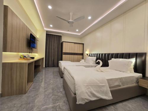 a hotel room with two beds and a ceiling fan at Mastiff Select Medha Plaza Deoghar in Deoghar