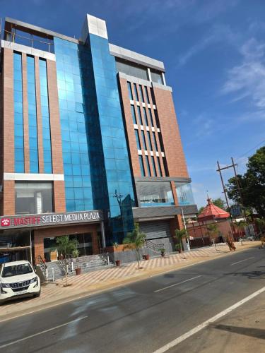 a building with a car parked in front of it at Mastiff Select Medha Plaza Deoghar in Deoghar