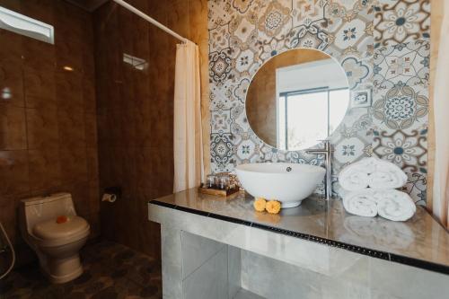 a bathroom with a sink and a mirror and a toilet at Dana's House in Tabanan