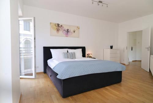 Un dormitorio con una cama grande en una habitación blanca. en Victoria Apartments, en Düsseldorf