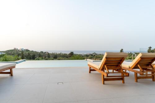 a patio with two wooden chairs and a pool at Star Luxury Villa - Private pool, gym, playground in Kato Daratso