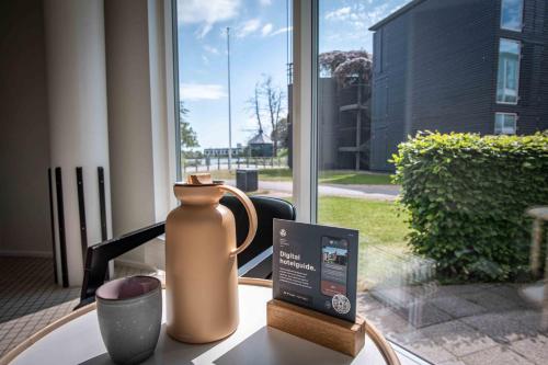 a vase sitting on a table in front of a window at Kolding Hotel Apartments in Kolding