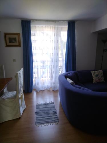 a living room with a blue couch and a large window at Nika in Ogulin