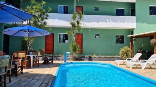 a pool in front of a hotel with chairs and umbrellas at Tamandaré Praia Hotel in Tamandaré