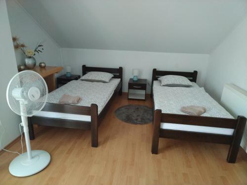 two beds in a room with a fan at Nika in Ogulin