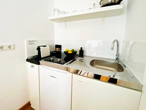 Una cocina con gabinetes blancos y un fregadero. en Victoria Apartments, en Düsseldorf