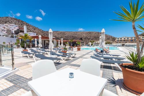 ein Resort mit weißen Tischen und Stühlen und einem Pool in der Unterkunft Apartment Sabi Star Puerto Rico in Puerto Rico de Gran Canaria