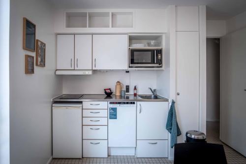 a kitchen with white cabinets and a white refrigerator at Kolding Hotel Apartments in Kolding