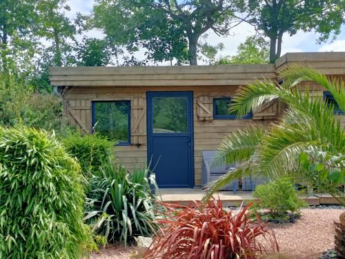 a tiny house with a blue door in a garden at Le Temps d'un Instant in Vattetot-sur-Mer