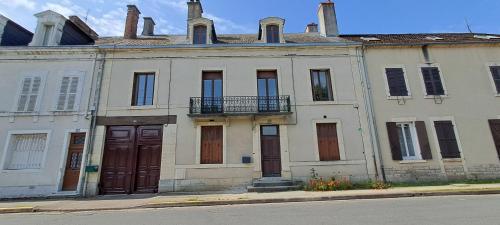 an old white building with a balcony on a street at Gite Aux Anciennes Ecuries in Sancoins