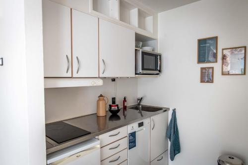 a white kitchen with a sink and a microwave at Kolding Hotel Apartments in Kolding