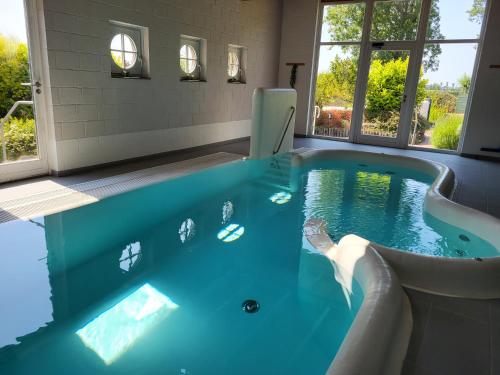 a hot tub in a room with blue water at Het Zilte in Zuidzande
