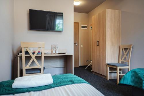 a room with a bed and a desk with a tv on the wall at Hotel Boginia in Boginia